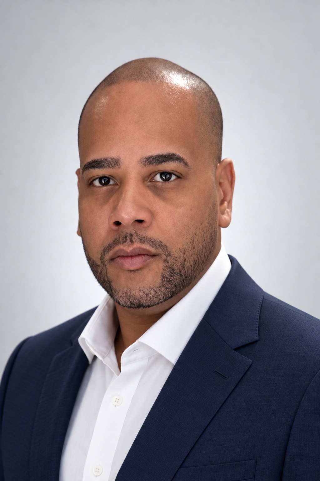 Studio portrait of Dennis Batten in a navy suit and open-collar white shirt.