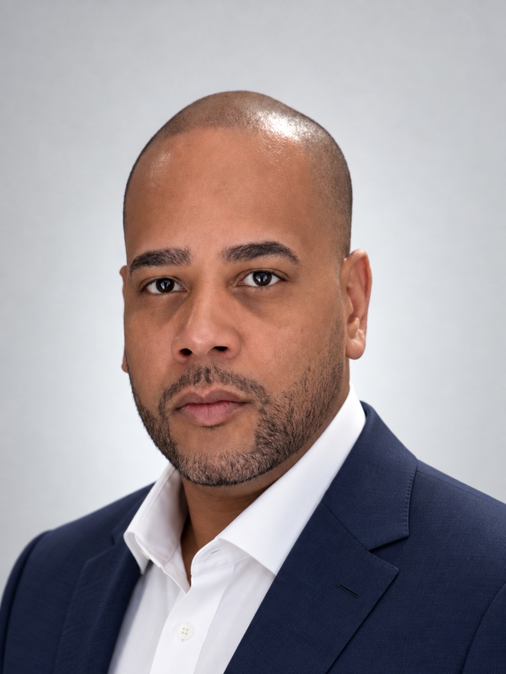 Studio portrait of Dennis Batten, founder of Xecutive Services, in a navy suit and open white collar.