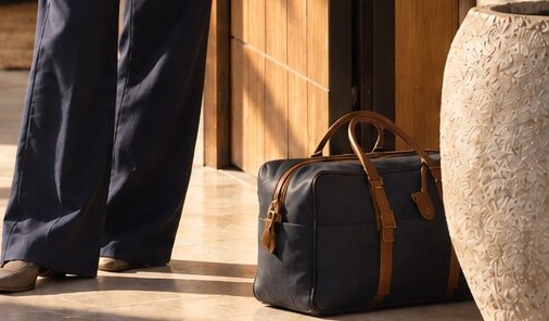 A packed weekend bag waits beside the open front door in the morning light.